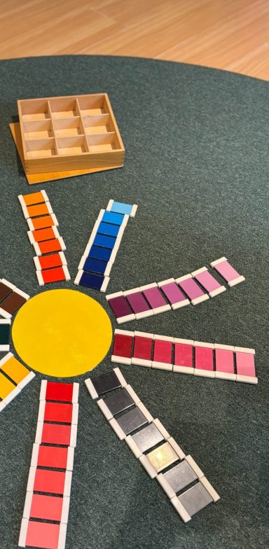 Färgglada kvadrater arrangerade i en solform på en grön matta.